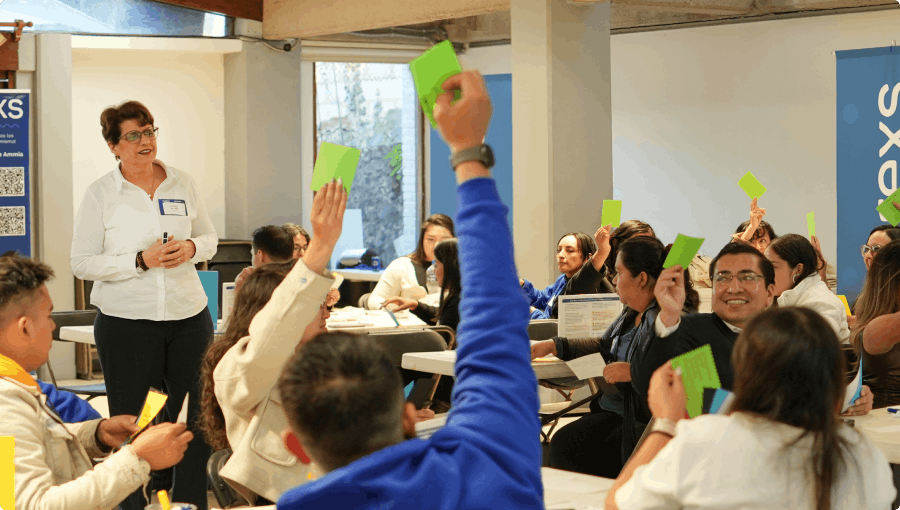 Participantes levantando tarjetas en dinámica grupal, vinculada a taller colaborativo para líderes y equipos en entorno corporativo.